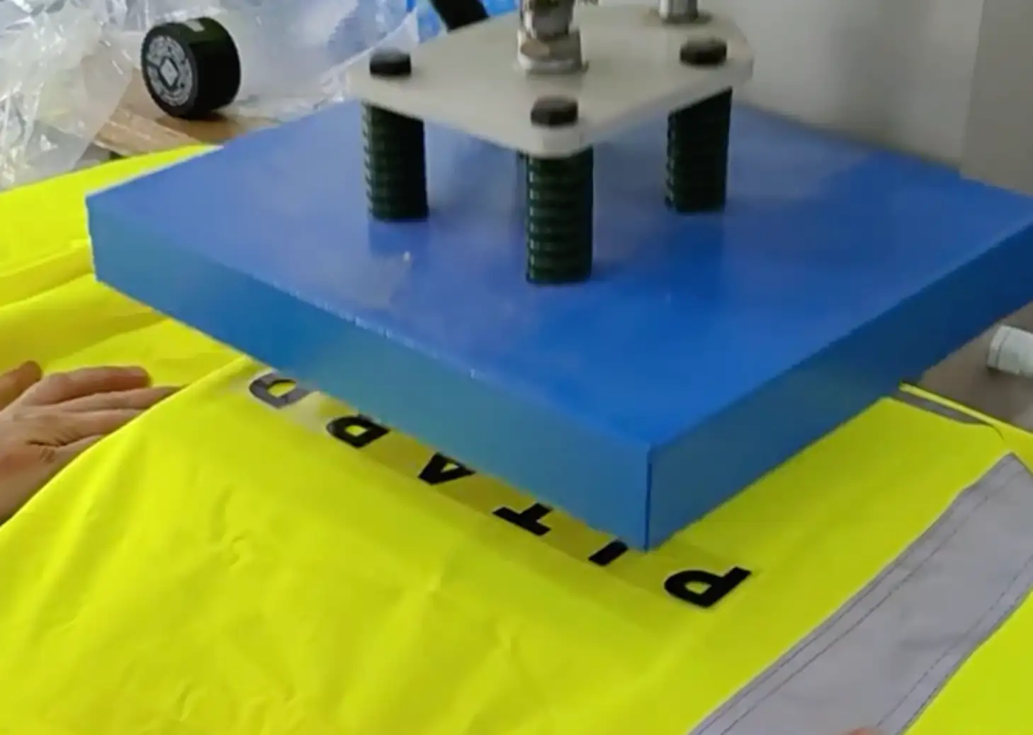 Heat press applying lettering to a high-visibility garment