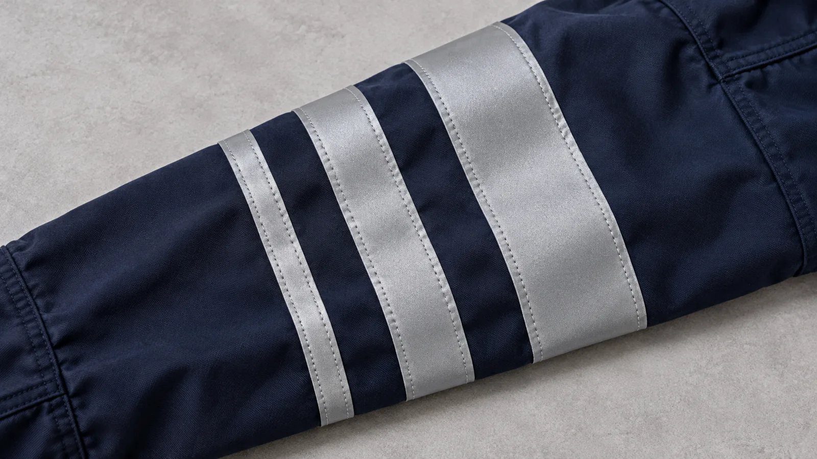 Close-up of silver reflective tape applied in three different widths along a workwear sleeve
